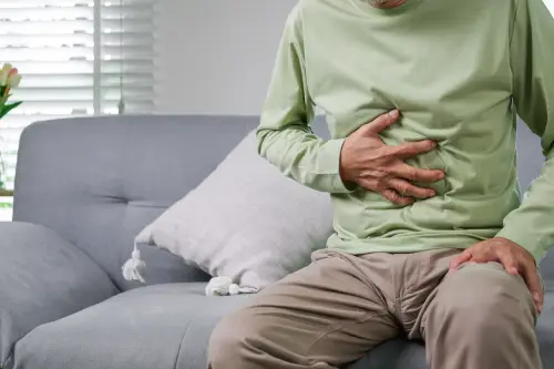 Hombre de polo verde con sintoma de estreñimiento